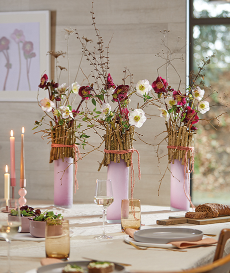 Hier wurden Aarendelle Nora Purple und Bella Picotee zusammen mit Ligustrum und Lunaria in Vasen mit Zweigrand auf dem Esstisch dekoriert.